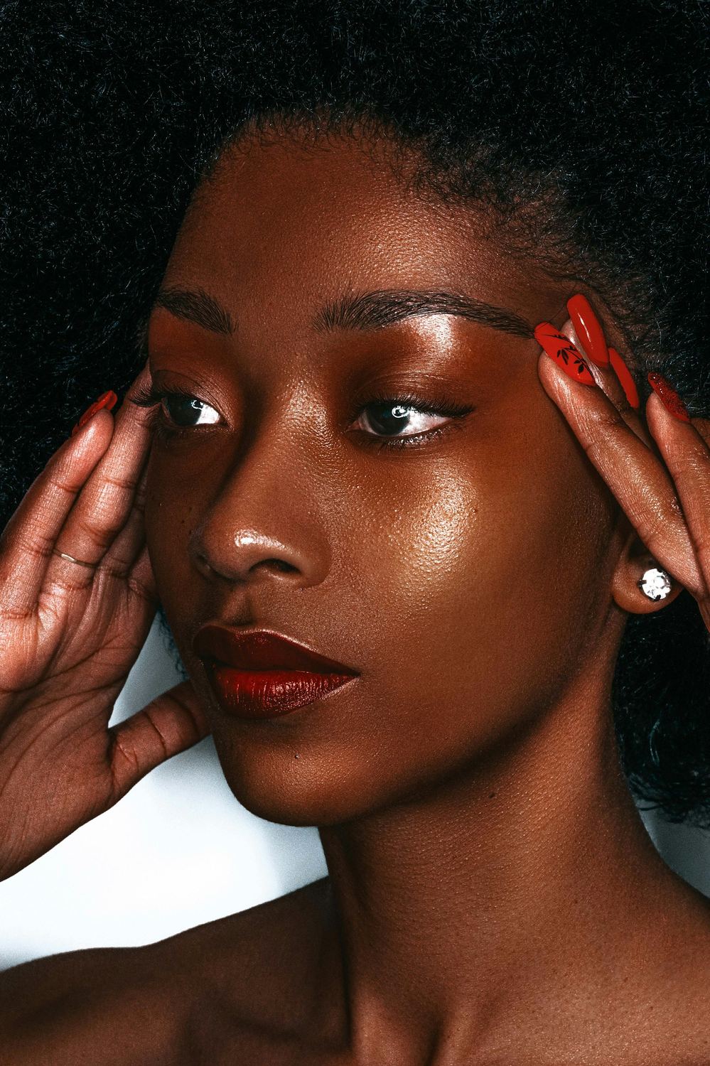 Portrait d’une femme à la peau noire, mains aux ongles rouges